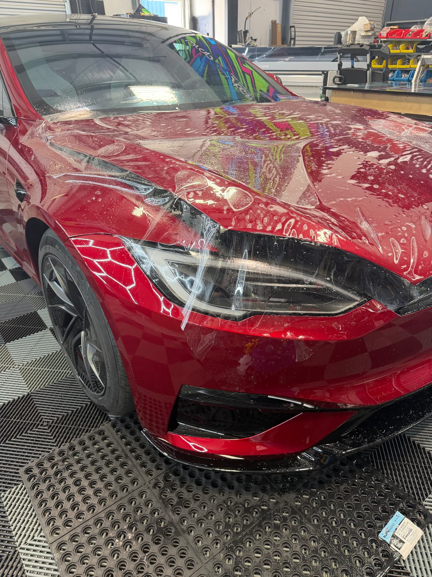 Paint protection film being installed on a red Tesla at LeWolf in Magnolia, TX