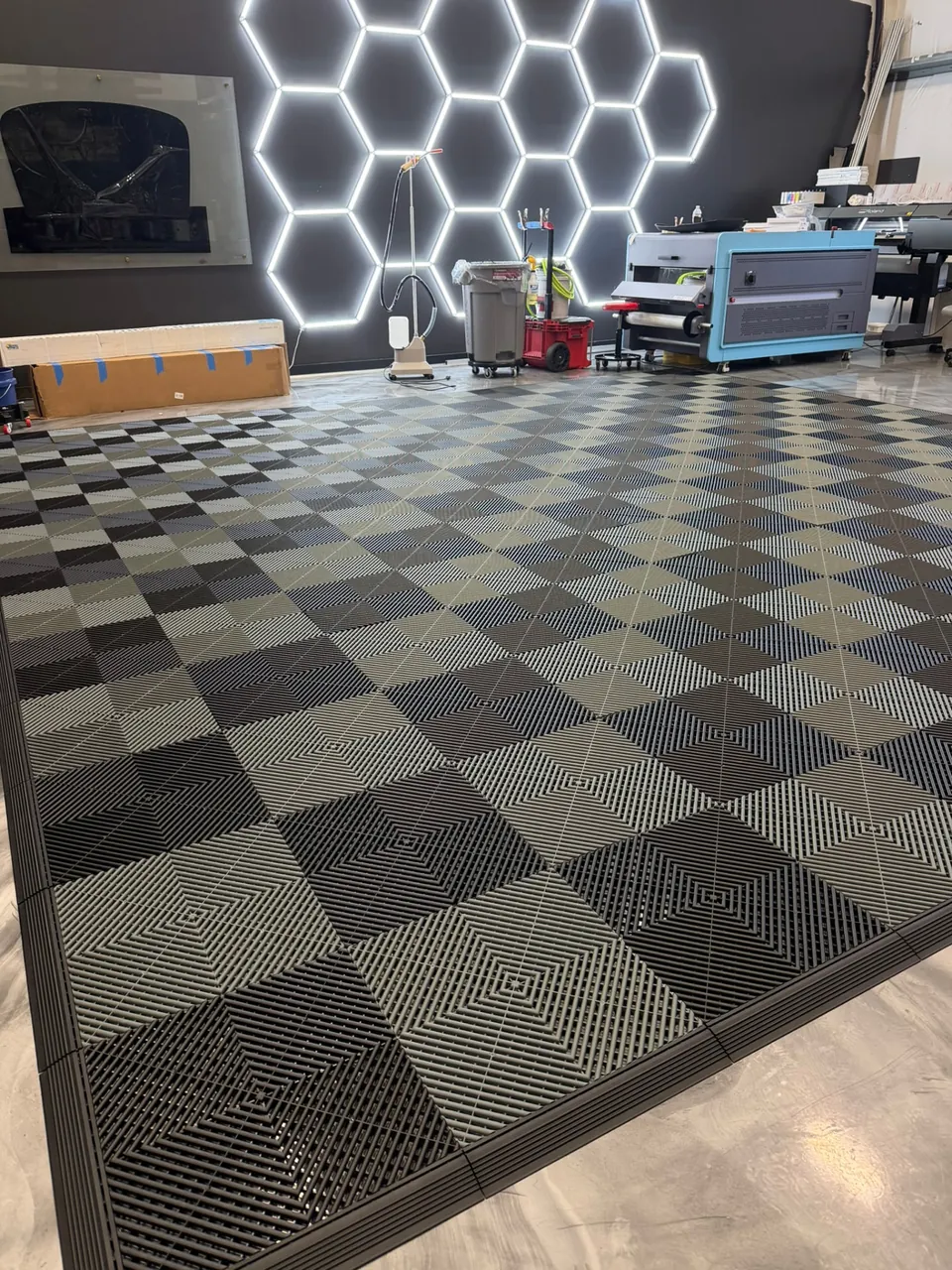 LeWolf Magnolia Texas install bay with checkered floor tiles, hexagon LED lighting, and print and laminating equipment