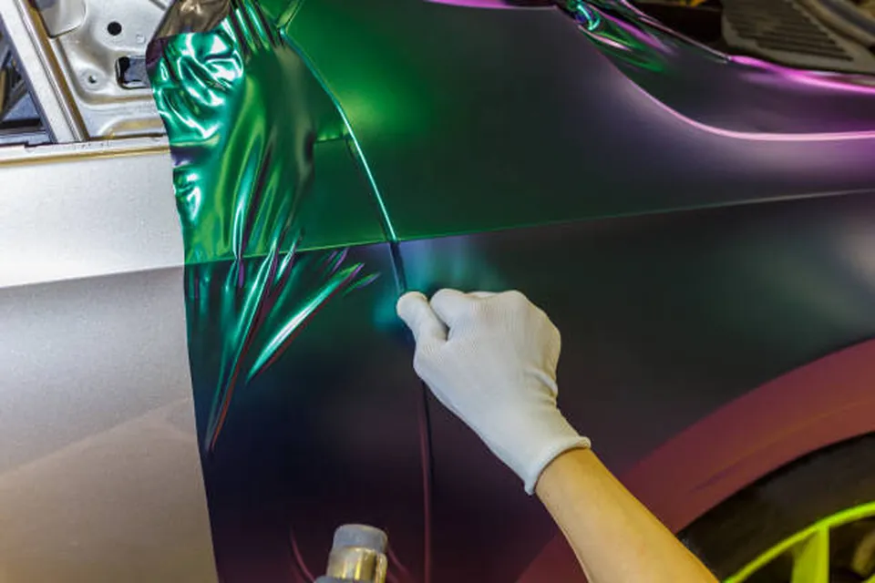 Installer smoothing a color-shift vinyl wrap onto a car fender in Magnolia, Texas